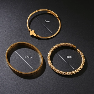 Detailed view of three gold-plated stainless steel bracelets with cross charm and twisted texture