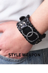Detail of a punk style wide black leather bracelet with silver intertwined snake rings