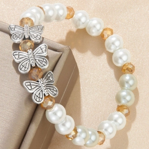 Minimalist pearl beaded bracelet with silver butterfly charms on champagne satin fabric