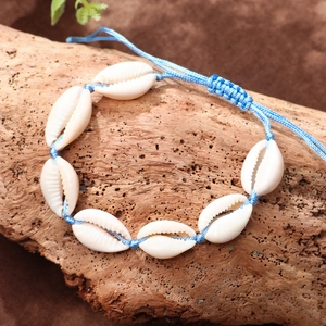 Handmade bohemian blue cord shell anklet with natural cowrie shells on a rustic wooden base