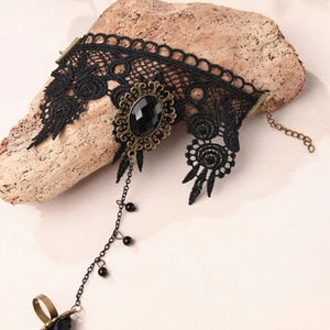 Gothic black lace slave bracelet with oval gemstone and ring on a tree bark surface