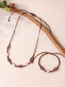 Détail d'un ensemble de bijoux Evil Eye tressés avec breloque cœur sur branche