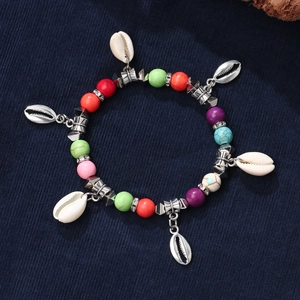 Bohemian turquoise bead bracelet with silver shell charms and heart pendant on blue background