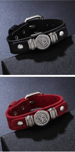 Detalle de pulseras vikingas de cuero con tótem de cabeza de lobo y símbolos rúnicos en negro