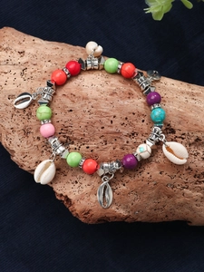 Detail of bohemian beaded bracelet with shell charms on a rustic wooden background