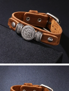 Detalle macro de pulsera de cuero marrón con medallón de cabeza de lobo y runas vikingas