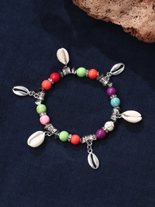 Detail of bohemian beaded bracelet featuring colorful stones and seashell charms on blue cloth
