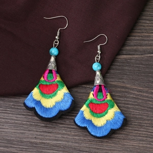 Detail of colorful ethnic embroidered fan earrings with blue turquoise beads and silver hooks