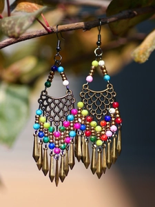 Detail of bohemian tassel earrings with colorful beads on a natural wood branch