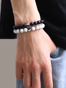 Gros plan de bracelets Yin Yang en perles noires mates et marbrées portés au poignet