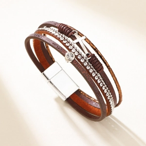 Mehrlagiges Lederarmband mit Kreuzanhänger und Magnetverschluss auf minimalistischem Beige