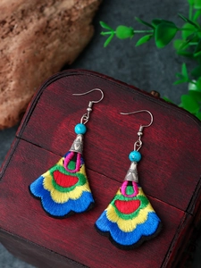 Close-up of bohemian fan-shaped embroidered earrings with turquoise beads and retro silver hooks