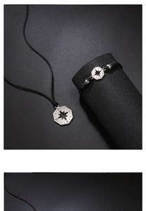 Detail of vintage silver compass pendant and braided bracelet set on black background