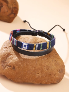 Detail of handmade ethnic woven strap and black leather cord on adjustable bracelet
