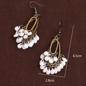 Vintage bohemian bronze drop earrings with white teardrop charms on dark fabric