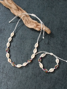 Handmade seashell necklace and bracelet set with daisy prints on stone background