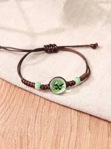 Macro view of handmade adjustable braided rope bracelet with a floral glass bead