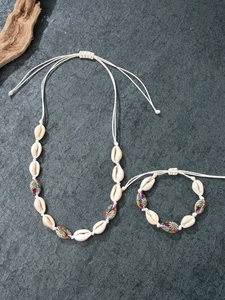 Close-up of handmade shell necklace and bracelet set with daisy patterns on stone base