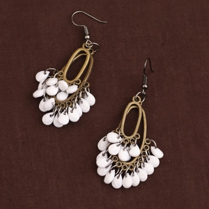 Vintage bronze drop earrings with bohemian fringe resin pearls on a textured dark fabric