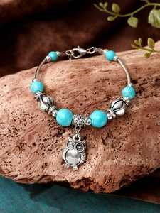 Close-up of vintage turquoise bead bracelet featuring a detailed silver owl charm