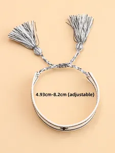 Dettaglio del bracciale intrecciato bohémien bianco e nero regolabile con nappe, 4,93-8,2 cm