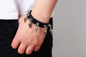 Detail of punk style black leather bracelet featuring five silver metallic cone spikes