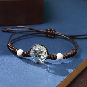 Handmade woven bracelet featuring a resin ball with butterfly and dried flowers
