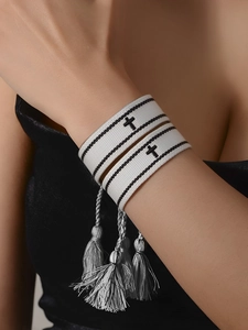 Dettaglio ravvicinato del bracciale in cotone intrecciato con croce nera e nappe