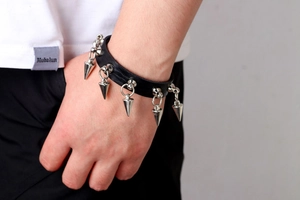 Close-up of punk black leather bracelet with silver metal cone spike rivets on wrist