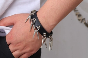 Gros plan d'un bracelet punk en cuir noir avec des pointes métalliques sur un poignet