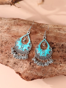 Close-up of bohemian water drop earrings with blue enamel detailing and metal bead tassels