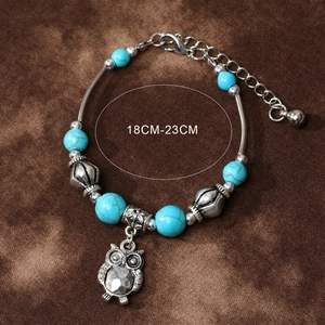 Retro turquoise beads bracelet with owl pendant and heart charm on dark background
