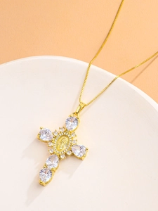 Detailed close-up of a golden cross pendant with teardrop crystals and a religious relief