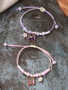 Detailed view of woven butterfly bracelets with adjustable cord and floral pendants