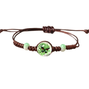 Handmade woven ceramic bracelet featuring a crystal bead with butterfly and plant inside