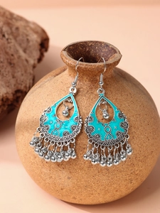 Detail of bohemian drop earrings with turquoise enamel and tassels on a ceramic pot