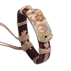 Dettaglio del bracciale vintage in pelle con corda di canapa e simbolo della pace