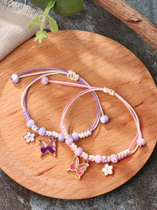Detail of two handmade woven butterfly and cherry blossom bracelets on wooden tray