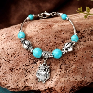 Retro turquoise beaded bracelet with heart and owl pendant on a wooden background