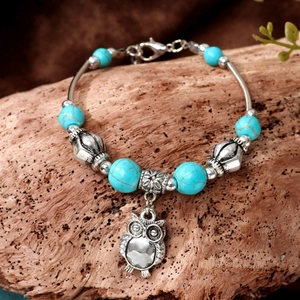 Retro Bohemian owl bracelet with turquoise beads and silver charms on rustic wood