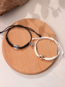 Detail of magnetic shell bracelets for couples with adjustable hand-woven rope on wood