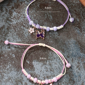 Handmade woven butterfly bracelet with floral charms and beads in purple and pink