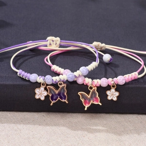 Handmade woven butterfly bracelet with floral charms in purple and pink tones