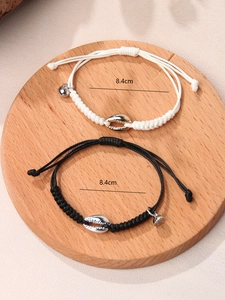 Detail view of woven couple bracelets with polished shell charms and tiny bells at 8.4cm size