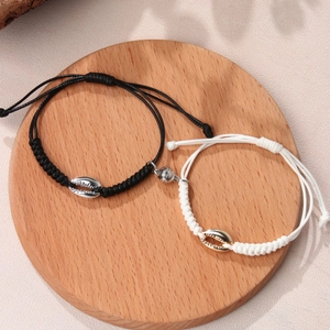 Magnetic couples bracelets with woven ropes and shell charms on a wooden display