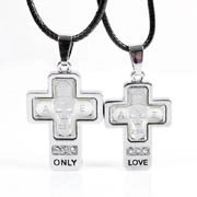 Close-up of silver cross pendants for couples featuring ONLY LOVE and AE engravings