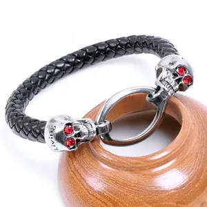 Detail of woven leather bracelet with silver metal skulls and red gemstone eyes