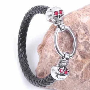 Macro detail of gothic leather bracelet with silver skulls and red crystal eyes