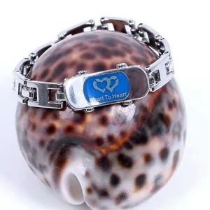 Détail d'un bracelet chaîne argenté avec plaque logo Heart To Heart sur un coquillage
