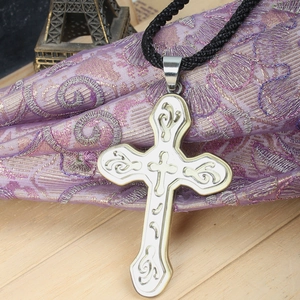 Detalle de un colgante de doble cruz de plata y oro con motivos filigranas en cordón negro